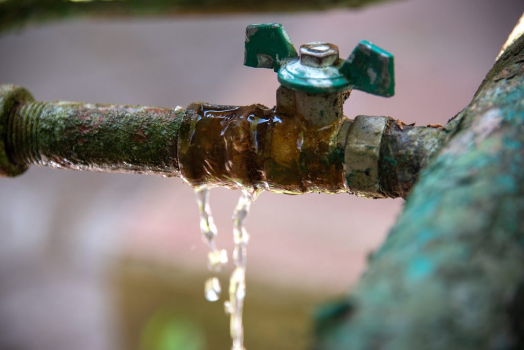 Corroded outdoor pipe with a slow leak, a common storm-season risk.